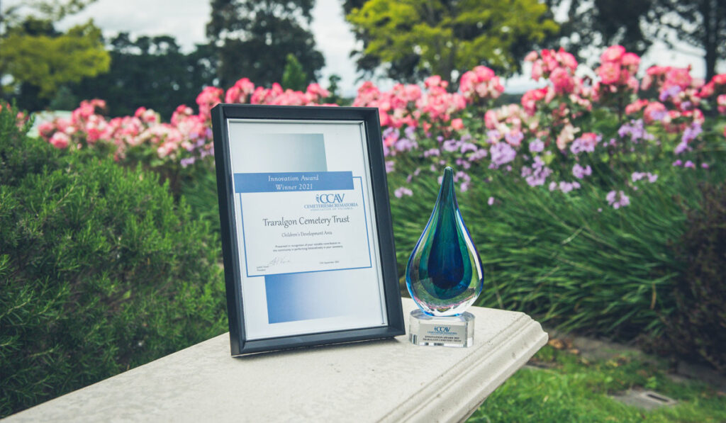 Framed award and glass trophy with garden in background