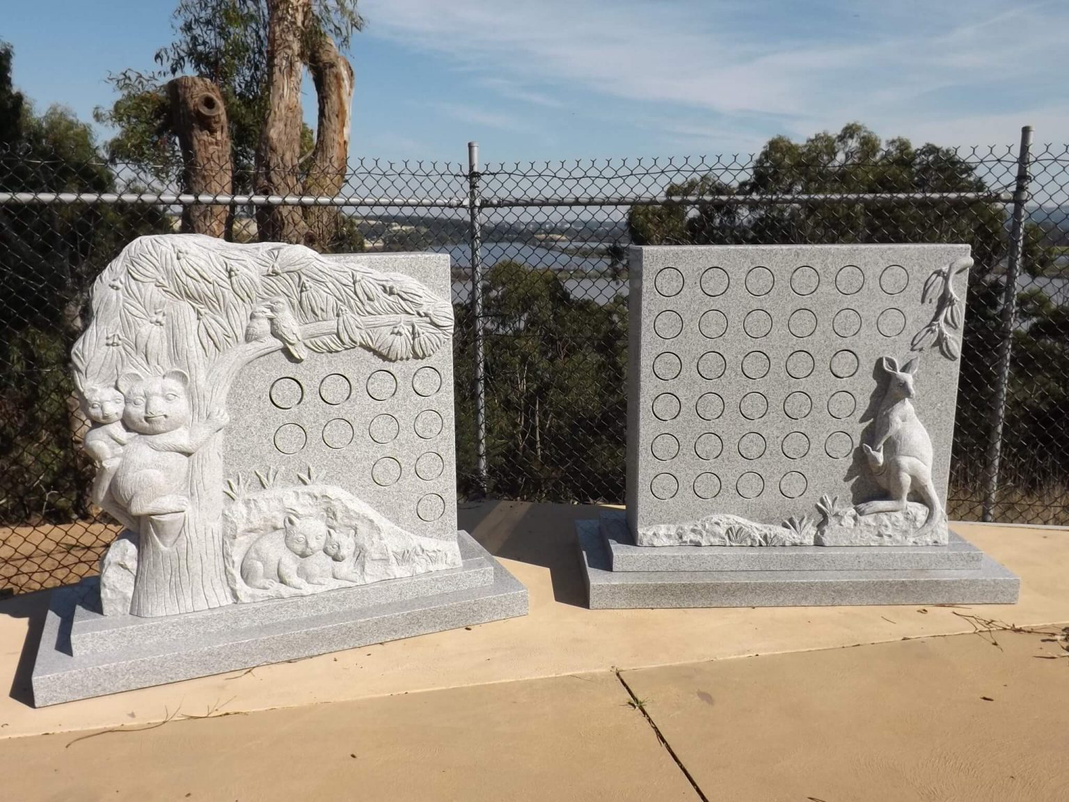 Two granite niche walls carved with animals in them overlooking water behind