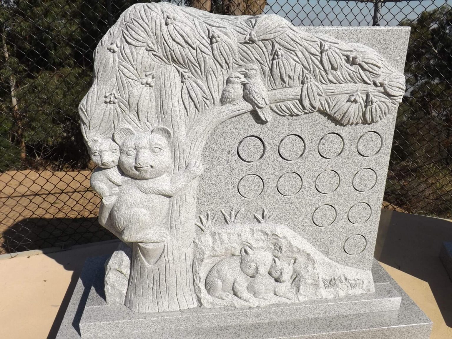 Granite Niche Wall with koala and baby on back in tree with kookaburras on branch above, all carved into granite wall