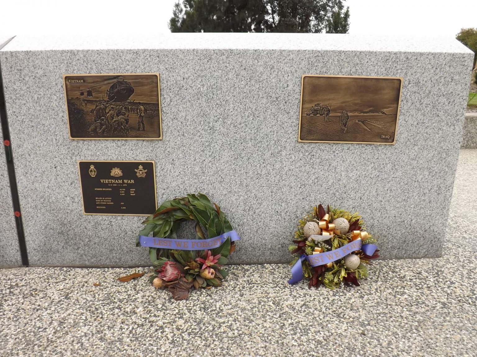 Granite Wall with three plaques on war and two wreaths at base