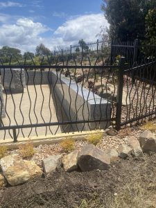 Rocks and stone wall behind decorative black fence