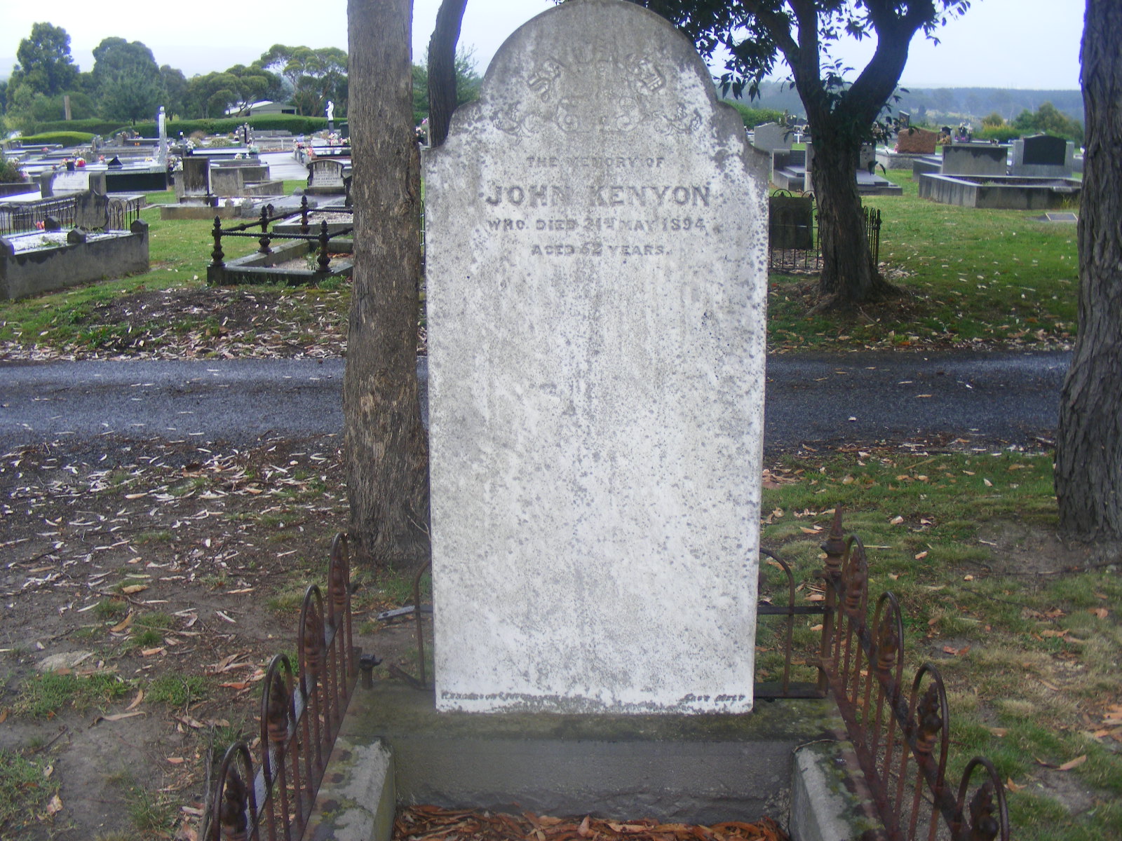Large white headstone with grave surrounds and old graves behind.