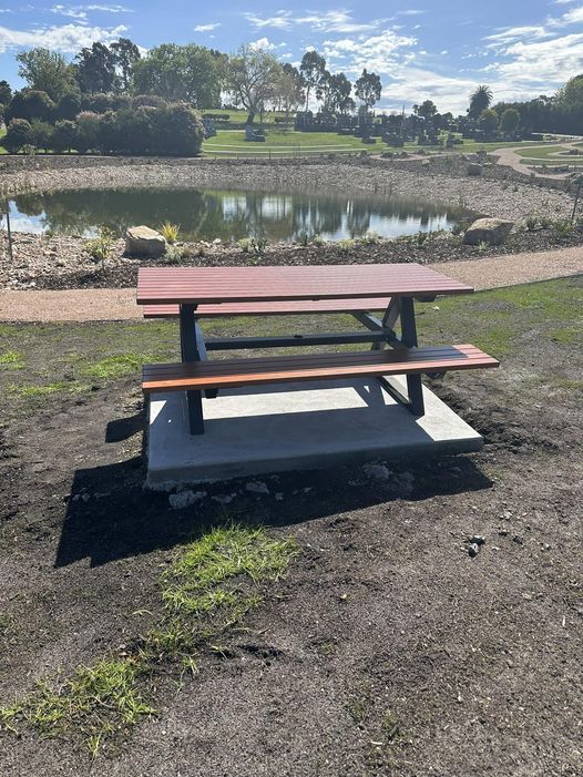 Brown picnic table on concrete pad overlooking lake