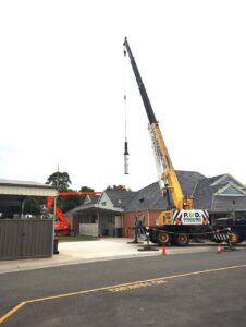 Crane lifting large cylinder above roof