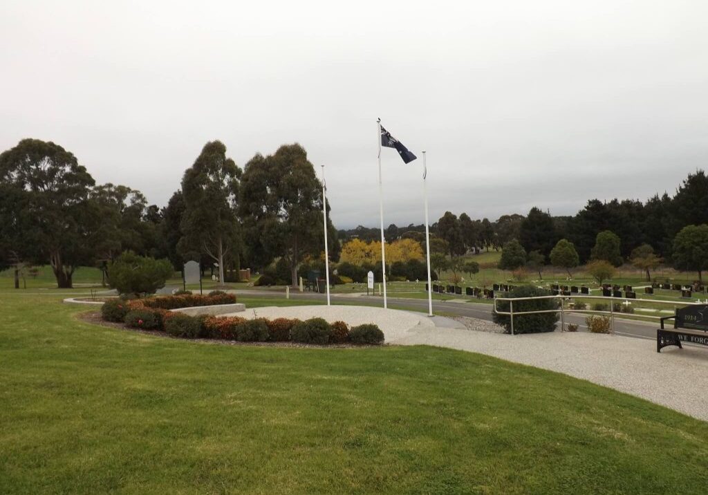 View overlooking war memorial with flag pole in centre. Graves behind