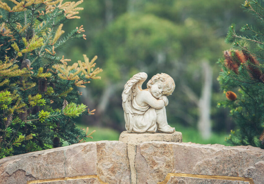 Cherub angle madeof stone sitting in a garden