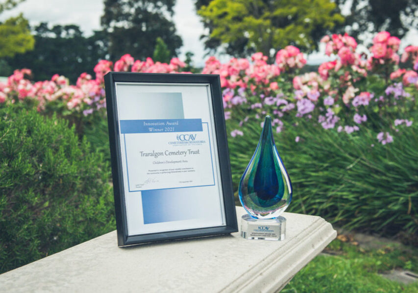 Framed award and glass trophy with garden in background