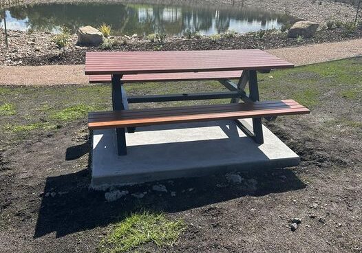 Brown picnic table on concrete pad overlooking lake